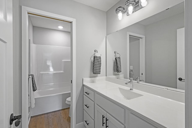 bathroom featuring wood finished floors, vanity, washtub / shower combination, and toilet