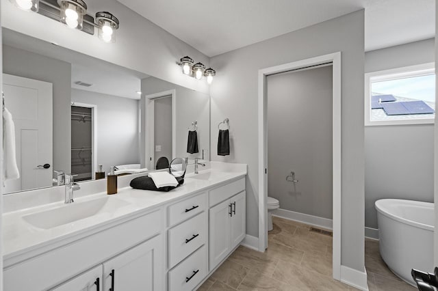 bathroom featuring a spacious closet, toilet, a sink, and double vanity