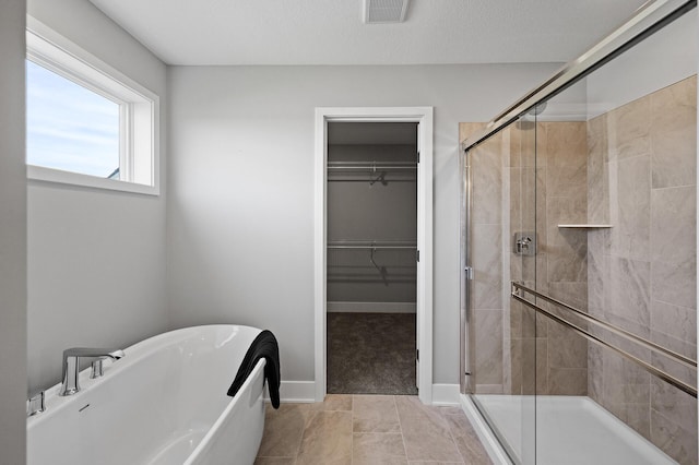 bathroom with a freestanding bath, a stall shower, baseboards, visible vents, and a spacious closet