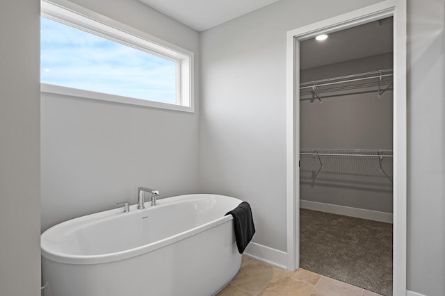 full bathroom featuring baseboards, a spacious closet, and a freestanding bath