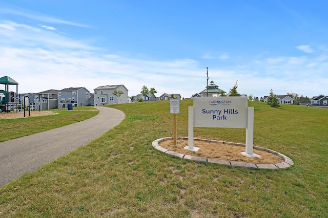 community sign featuring a yard and a residential view