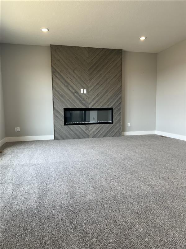 unfurnished living room with recessed lighting, baseboards, carpet floors, and a fireplace