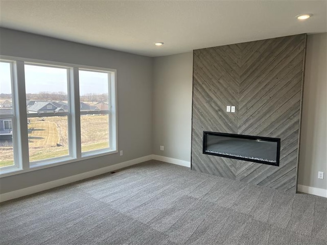unfurnished living room featuring baseboards, carpet flooring, a large fireplace, and recessed lighting