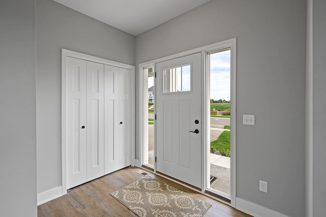 foyer entrance featuring baseboards, wood finished floors, and visible vents