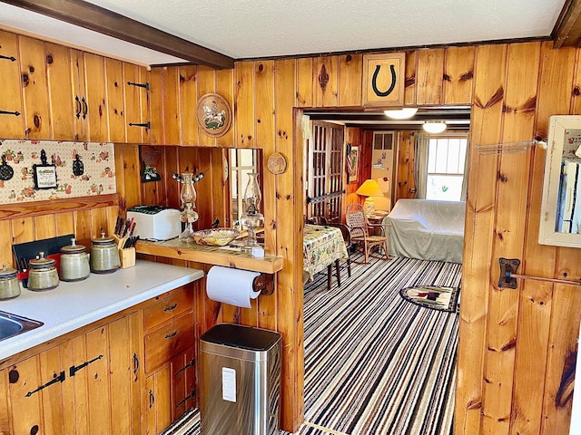 357 Glenmar Dr NE, Longville, MN 56655 - kitchen with wood walls, beam ceiling, light countertops, and brown cabinetry