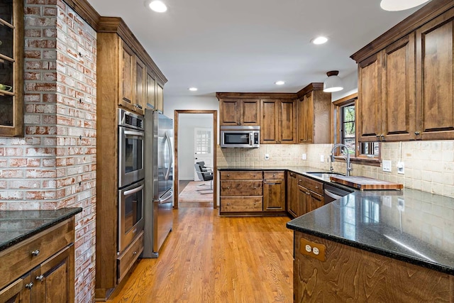 5 Shore Rd, North Oaks, MN 55127 - kitchen with stainless steel appliances, a sink, dark stone countertops, light wood finished floors, and decorative backsplash