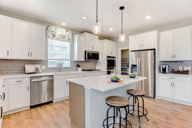 528 Goldenrod Trl, Waconia, MN 55387 - kitchen with stainless steel appliances, decorative backsplash, a breakfast bar, light wood finished floors, and recessed lighting