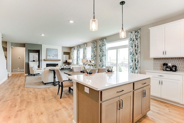 528 Goldenrod Trl, Waconia, MN 55387 - kitchen with a center island, light countertops, decorative backsplash, light wood-style floors, and decorative light fixtures
