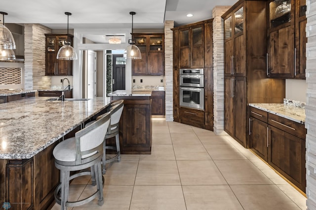 kitchen with a sink, a center island with sink, light tile patterned flooring, glass insert cabinets, and recessed lighting