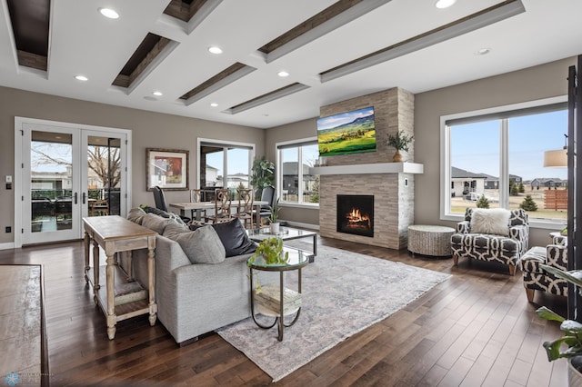 living area featuring a stone fireplace, dark wood-style floors, beamed ceiling, recessed lighting, and french doors
