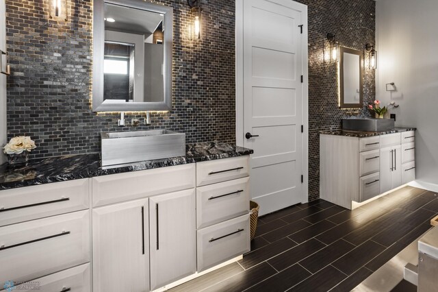 bathroom featuring backsplash, two vanities, and wood finished floors