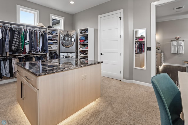 walk in closet featuring stacked washer and clothes dryer and light colored carpet