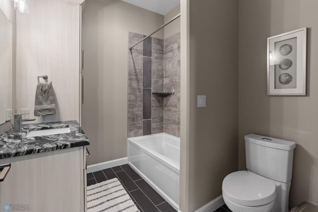 bathroom with baseboards, toilet, vanity, and shower / washtub combination