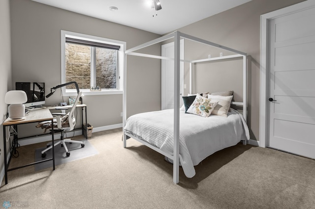 bedroom with carpet, an office area, and baseboards