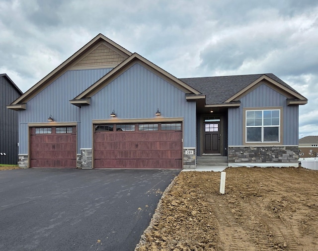 249 3rd St SW, Delano, MN 55328 - view of front of property with stone siding, asphalt driveway, an attached garage, and board and batten siding