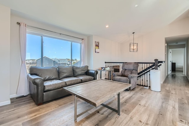 living area featuring a chandelier, light wood-type flooring, and baseboards