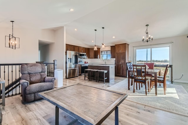 living room featuring recessed lighting, vaulted ceiling, an inviting chandelier, and light wood-style floors