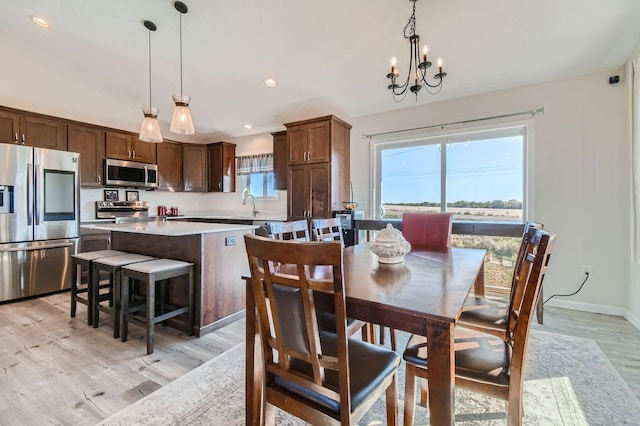 dining space with light wood-type flooring, baseboards, recessed lighting, and a notable chandelier