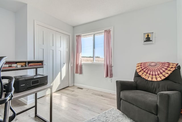 sitting room with baseboards and light wood-style flooring
