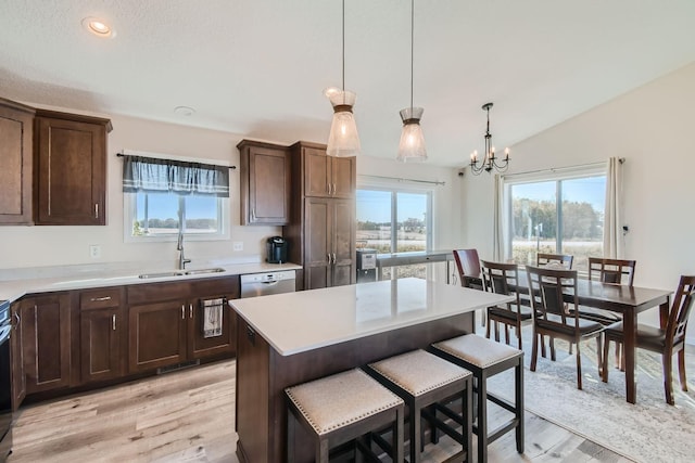 kitchen featuring dark brown cabinets, a sink, dishwasher, light wood finished floors, and light countertops