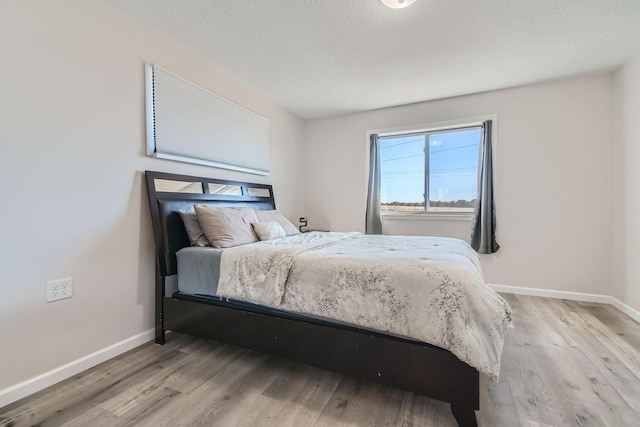 bedroom featuring wood finished floors, baseboards, and a textured ceiling