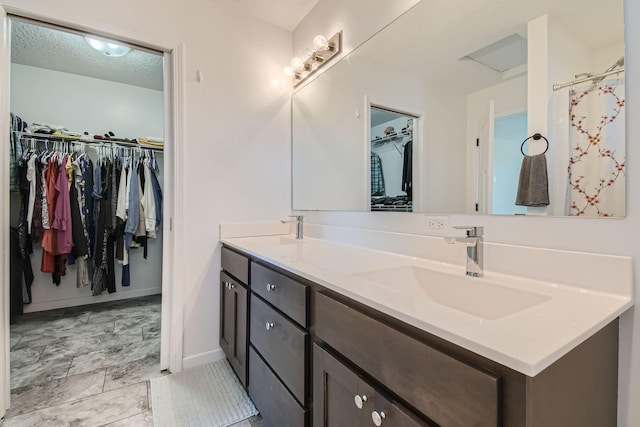 bathroom with a spacious closet, baseboards, a sink, and double vanity