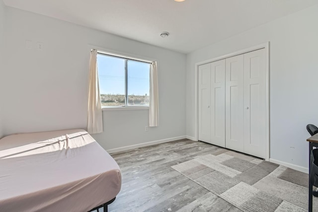 bedroom with baseboards, wood finished floors, and a closet