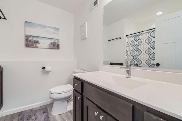 bathroom featuring toilet, vanity, wood finished floors, and visible vents