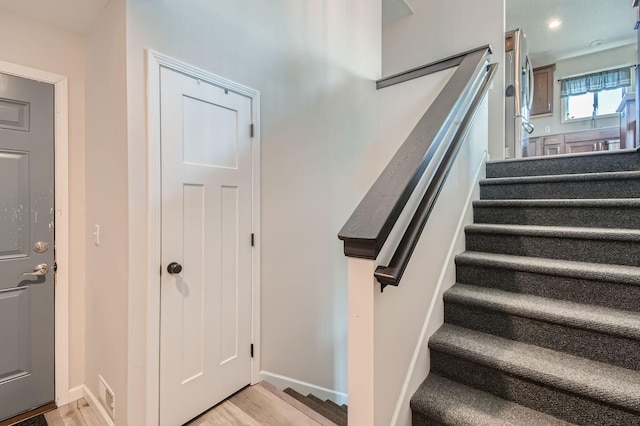 stairway with recessed lighting, wood finished floors, and baseboards