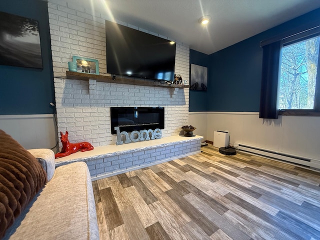 living room featuring a wainscoted wall, wood finished floors, a brick fireplace, and baseboard heating
