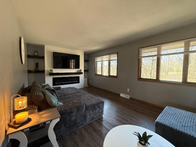 living area featuring a textured ceiling, wood finished floors, a fireplace, and baseboards