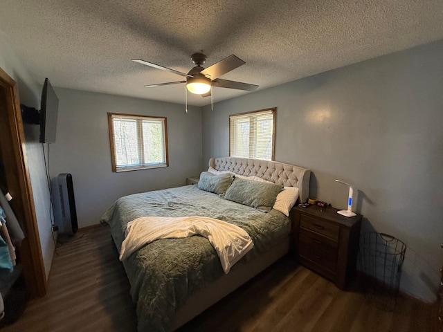 bedroom with dark wood finished floors, multiple windows, a textured ceiling, and a ceiling fan