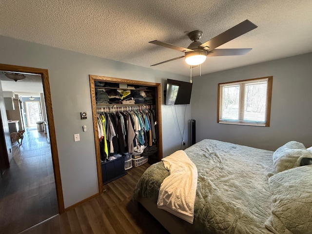 bedroom with multiple windows, dark wood finished floors, a closet, a textured ceiling, and a ceiling fan