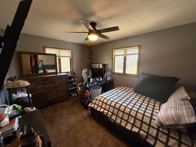 bedroom featuring multiple windows, tile patterned floors, a textured ceiling, and a ceiling fan