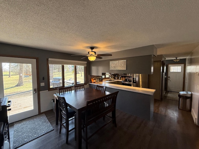 dining room with a textured ceiling, dark wood finished floors, a ceiling fan, and baseboards