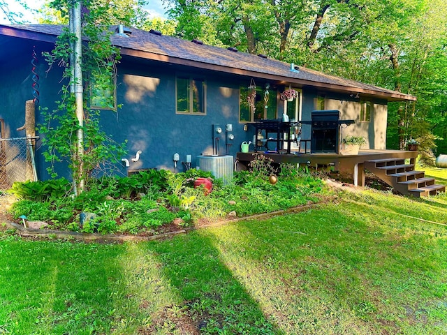 view of front facade featuring a wooden deck, a front yard, stucco siding, stairs, and central AC unit