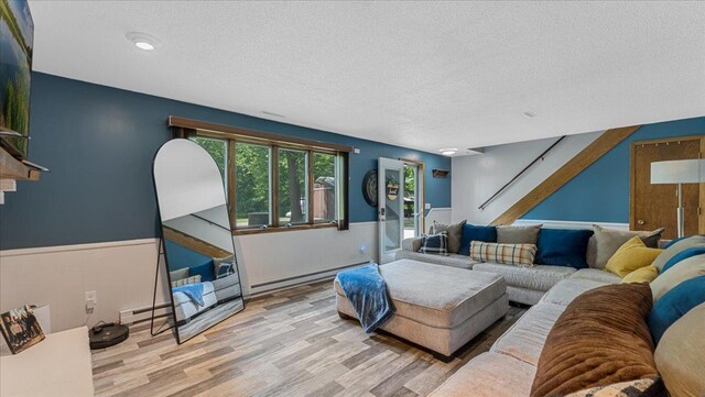 19593 Minnesota Highway 22, Greenleaf Twp, MN 55355 - living area featuring baseboard heating, a textured ceiling, a wainscoted wall, wood finished floors, and stairway