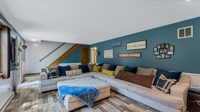 19593 Minnesota Highway 22, Greenleaf Twp, MN 55355 - living area featuring baseboard heating, wood finished floors, a textured ceiling, and stairs