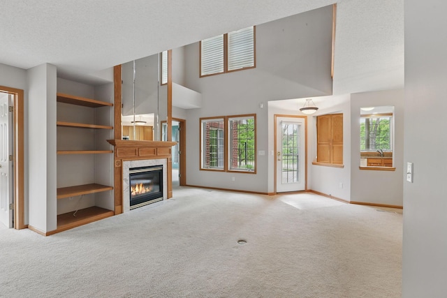 13409 44th Cir NE, Saint Michael, MN 55376 - unfurnished living room featuring light carpet, a fireplace, baseboards, a towering ceiling, and a textured ceiling