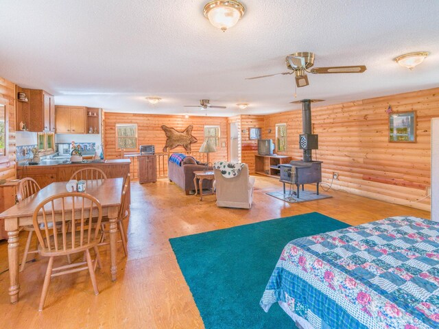 10823 Bollenbacher Rd, Garrison Twp, MN 56401 - bedroom with rustic walls, a wood stove, a textured ceiling, and light wood-type flooring