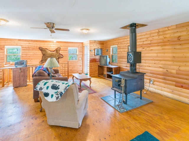 10823 Bollenbacher Rd, Garrison Twp, MN 56401 - living area with ceiling fan, rustic walls, a wood stove, and light wood-type flooring