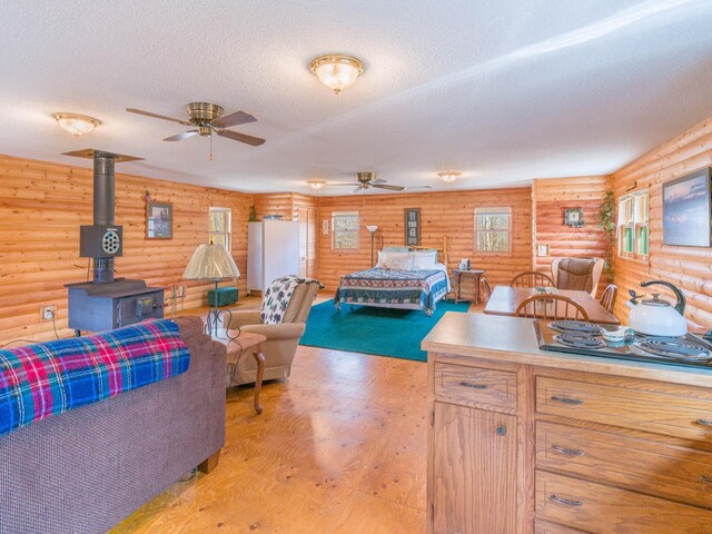 10823 Bollenbacher Rd, Garrison Twp, MN 56401 - interior space featuring rustic walls, a wood stove, a textured ceiling, and light wood finished floors