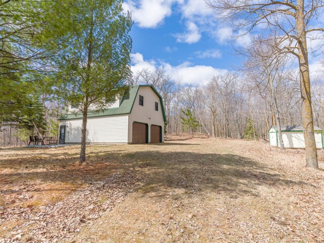 10823 Bollenbacher Rd, Garrison Twp, MN 56401 - exterior space featuring an attached garage, driveway, an outdoor structure, and a storage shed