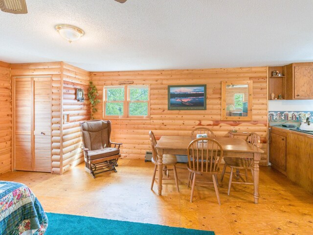 10823 Bollenbacher Rd, Garrison Twp, MN 56401 - dining room featuring log walls, light wood-style flooring, and a textured ceiling