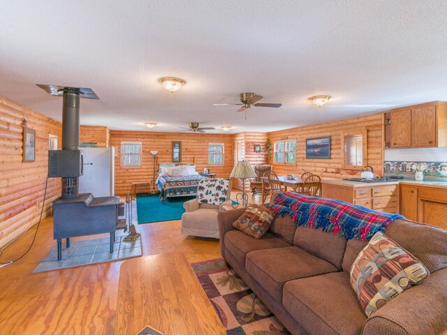 10823 Bollenbacher Rd, Garrison Twp, MN 56401 - living area featuring plenty of natural light, rustic walls, a wood stove, and light wood-style flooring