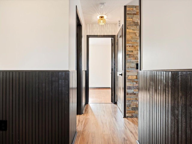 hallway with a wainscoted wall and light wood-style flooring
