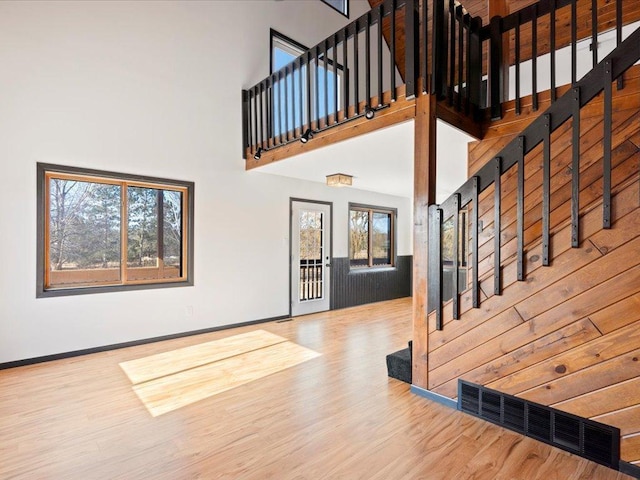 entryway featuring stairs, wood finished floors, a high ceiling, and baseboards