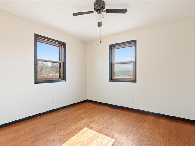 unfurnished room with baseboards, light wood-style floors, and a ceiling fan