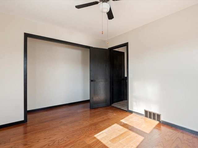 empty room featuring wood finished floors, a ceiling fan, and baseboards