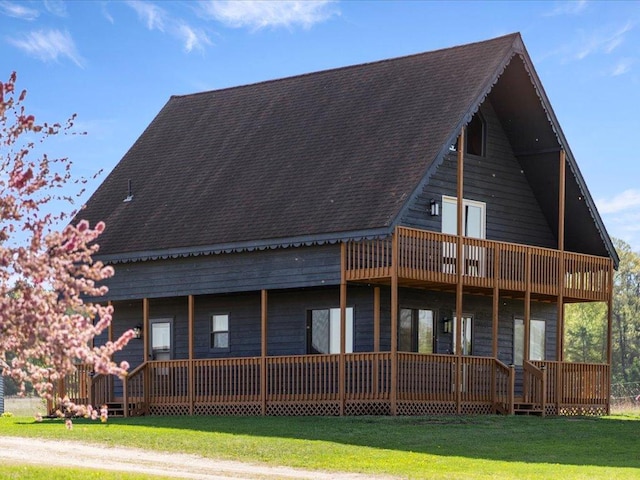 back of house featuring a lawn and a shingled roof